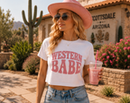 Woman wearing white Western Babe crop tee styled with pink cowboy hat and denim