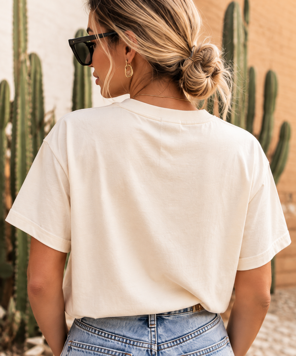 Blonde woman wearing the Howdy Darlin’ crop tee from the back with denim shorts