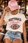 Woman wearing the Scottsdale Blonde crop tee with denim shorts and a pink Darlin’ Co. hat