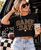 Woman wearing the black Game Day crop tee styled with denim shorts and sunglasses