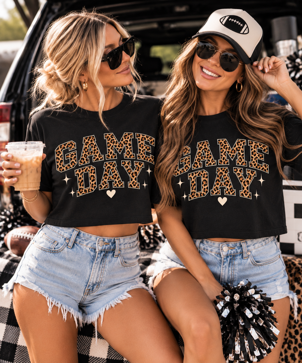 Two women wearing black Game Day crop tees styled with denim shorts