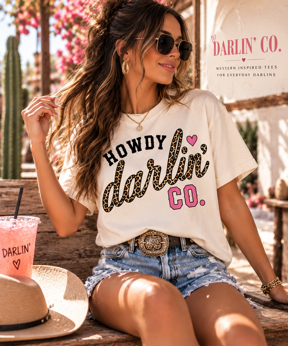 Brunette woman sitting in a Howdy Darlin’ Vintage White crop tee and denim shorts