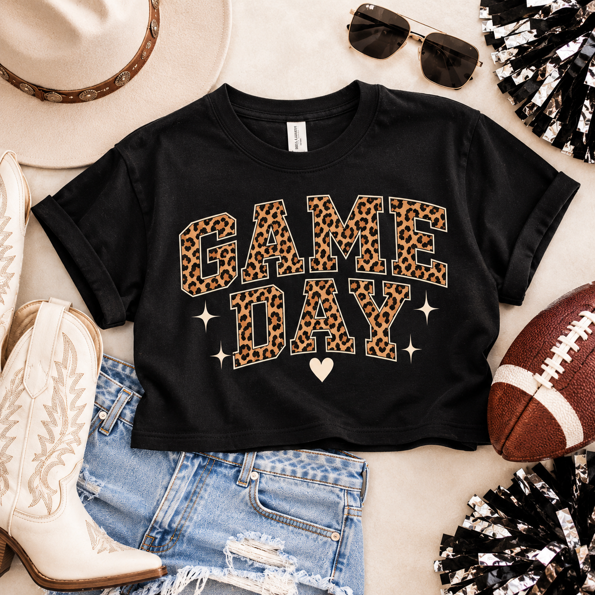 Black Game Day crop tee styled in a football-inspired flat lay