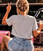Back view of woman wearing the Tequila & Touchdowns crop tee with denim shorts